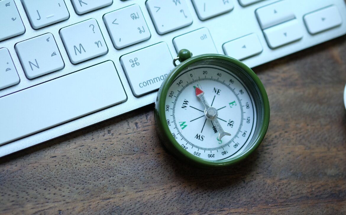 Kompass liegt auf einer Mac-Tastatur.