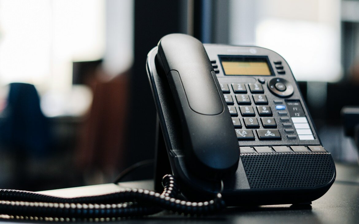 Schwarzes Telefon auf einem Schreibtisch. Symbolisch für VoIP-Telefonanlage von NOVGAO.