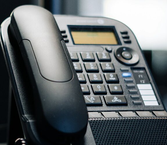 Schwarzes Telefon auf einem Schreibtisch. Symbolisch für VoIP-Telefonanlage von NOVGAO.