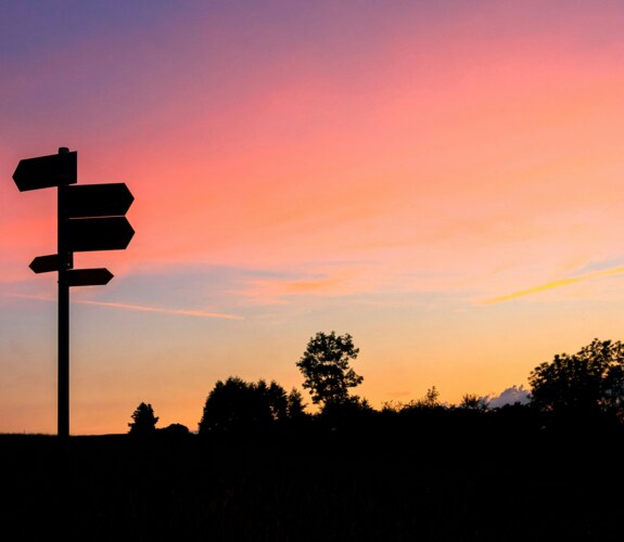 Wegweiser im Abendlicht als Symbol für den geplanten Wechsel von Windows 10 zu Windows 11 in Unternehmen.