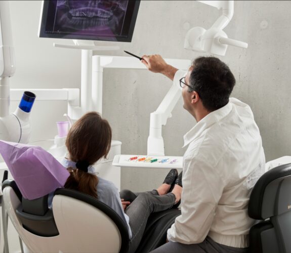 Zahnarzt erklärt Patientin digitale Röntgenbilder, Symbolbild für IT-Betreuung von Zahnärzten in Berlin durch NOVAGO.